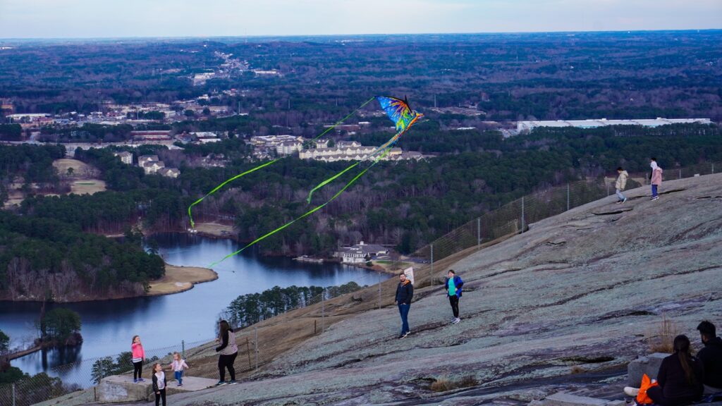 a group of people flying kites on top of a mountain